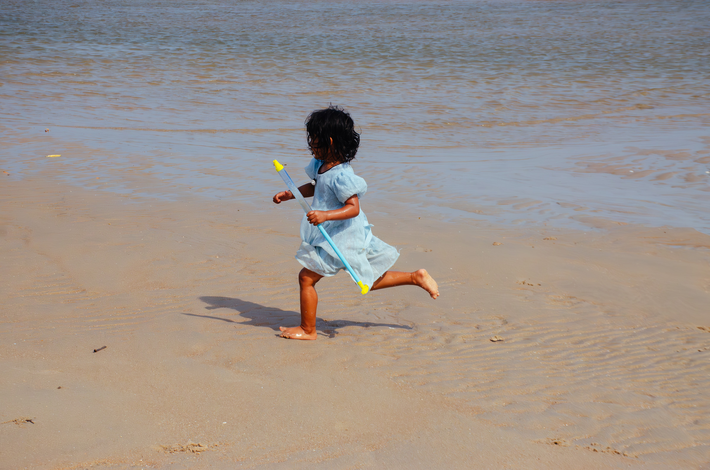 Child running along the beach at low tide